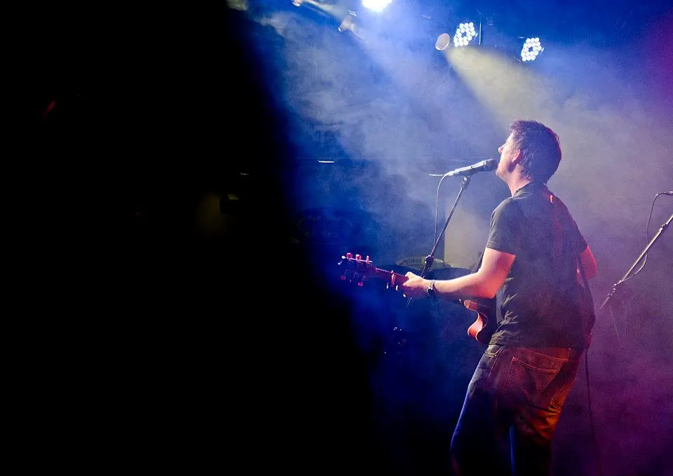 Ryan Inglis performing live on a stage lit in blue