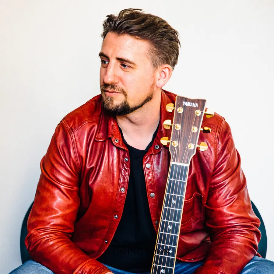 Ryan Inglis, guitar teacher in Munich, holding his acoustic guitar