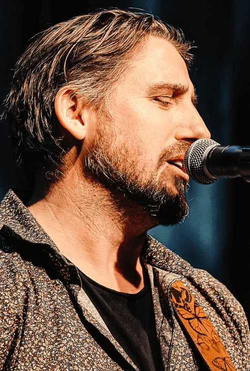 Ryan Inglis singing and playing acoustic guitar on stage